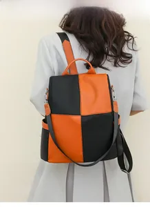 Detail of a casual color-block backpack in black and orange showing the side pocket and strap
