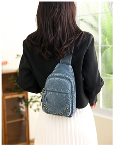Détail d'un sac de poitrine vintage en cuir bleu avec clous et pompons sur un mannequin