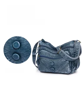 Detail of vintage blue crossbody bag with multi-zipper pockets and rivet decor