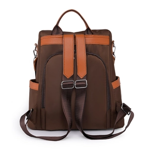 Deep brown waterproof nylon backpack with orange leather accents and dual-use design