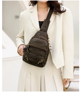 Détail du sac de poitrine vintage marron à rivets dorés porté sur un blazer blanc