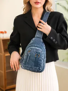 Detail of blue textured crossbody bag with metal zippers and adjustable strap for women