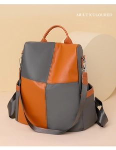 Detail of color-block grey and orange nylon backpack with top handle and side pockets