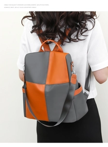 Detail view of contrast color gray and orange backpack with anti-theft back zipper opening