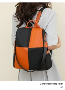 Detail of color-block casual backpack with orange leather handle and black nylon fabric