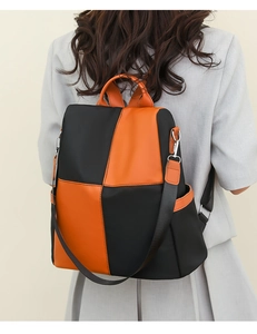 Detail of a color-block women's backpack featuring orange and black contrast panels