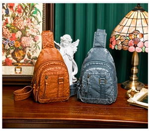 Detail of vintage washed leather chest bags in brown and blue with multi-zipper pockets