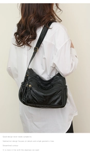 Close-up of black washed leather crossbody bag with multiple zippers and adjustable strap