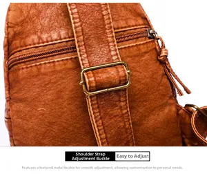Detail of adjustable strap with vintage bronze buckle on litchi texture leather bag