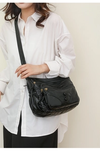 Detail of black multi-pocket crossbody bag in soft washed leather with gold zippers