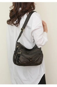 Detail view of black washed leather crossbody bag with multiple zippers and retro hardware