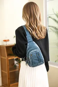 Detailed view of blue washed PU leather chest bag with multiple bronze zipper pockets