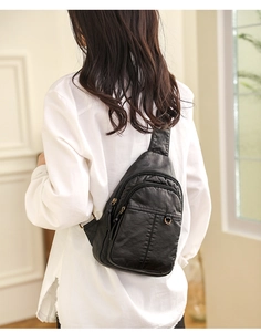 Schwarze Damen-Brusttasche aus weichem PU-Leder, getragen von einem Modell im Innenraum