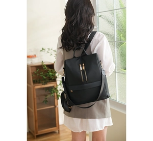 Vista posteriore di uno zaino nero elegante in tessuto oxford impermeabile con zip dorate