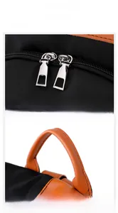 Detailed macro view of silver dual zippers and orange leather handle on black nylon bag