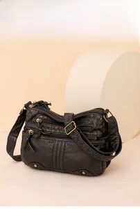 Détail du sac bandoulière en cuir lavé noir avec plusieurs poches zippées métalliques