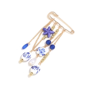 Detail of star charm and porcelain bead pendant on ethnic gold tassel brooch pin