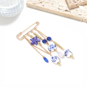Detail of starfish brooch with ceramic blue and white beads and hanging gold chains