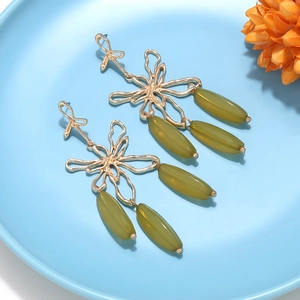 Detail of gold floral hollow earrings featuring three olive green olive-shaped pendants