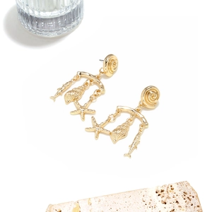 Detailed view of gold ocean-themed tassel earrings with starfish and shell charms