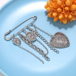 Detail of vintage silver heart chain brooch with ornate floral engraving on light blue tray