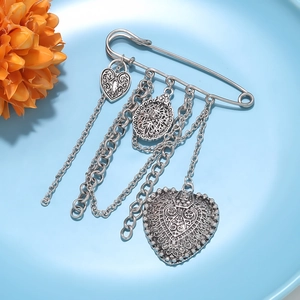Detail of vintage silver heart chain brooch with engraved tassels and large pin