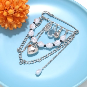 Detail of silver safety pin brooch with multi-layered chains and pearl heart charms