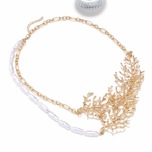 Detailed shot of golden coral branch pendant and baroque pearls on a layered necklace