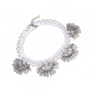 Detail of layered baroque pearl necklace featuring silver sunburst pendants and extension chain