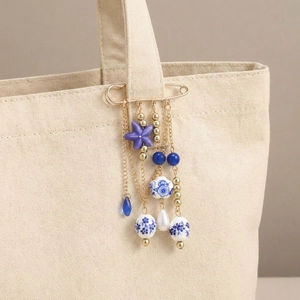 Vintage gold safety pin brooch with ceramic starfish and blue beads on beige canvas bag