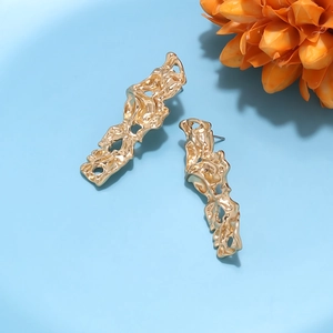 Detailed view of long gold lava texture earrings on a light blue background