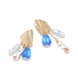 Detailed view of seahorse and baroque pearl earrings with shell and blue bead accents