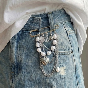 Retro silver safety pin brooch with heart charms and pearl tassels on denim skirt