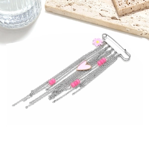 Detail view of a silver safety pin brooch with pink heart, daisy, and long chain tassels