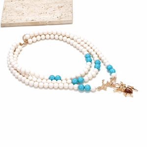 Dettaglio della collana a strati con perle turchesi e un ciondolo a forma di scarabeo