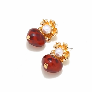 Detailed view of floral gold earrings with pearls and red leopard resin pendants
