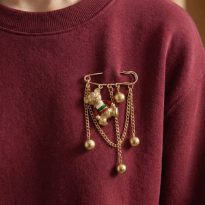 Broche ours doré mignonne avec rayures colorées et pompons clochettes sur pull rouge