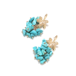 Detail of bohemian drop earrings with golden leaf accents and turquoise stone clusters