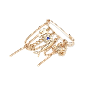 Detailed view of gold safety pin brooch with tropical leaf, fish, and crab charms