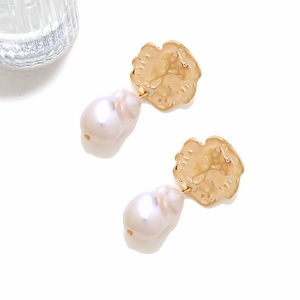 Detail view of gold hammered coin metal and baroque pearl drop earrings on white background