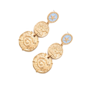 Détail de boucles d'oreilles vintage dorées avec texture martelée et étoile de mer