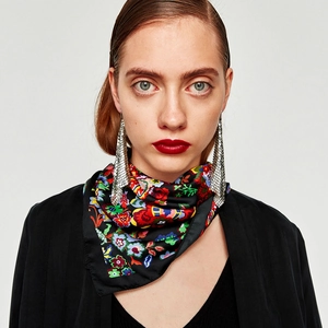 Detail view of long silver mesh fringe earrings paired with a vibrant floral silk scarf