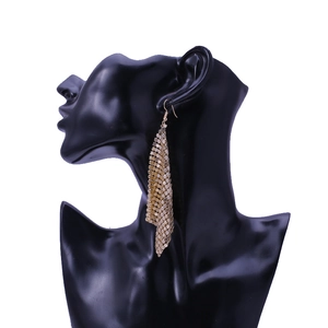 Detail shot of long golden sequin mesh tassel earring on a black display mannequin