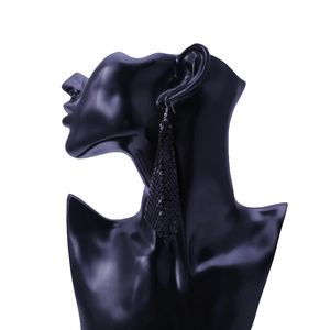 Detail of long black metal sequin tassel earrings on model display stand