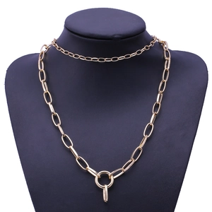 Detail of layered gold link necklace with circular pendant on black mannequin stand