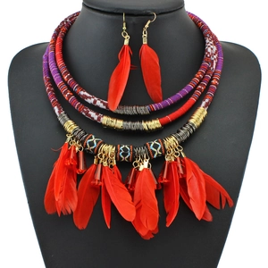 Detail of bohemian jewelry set featuring woven ropes and vibrant red feather pendants