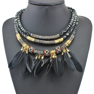 Detail of bohemian layered necklace featuring colorful ethnic ribbons and black feathers