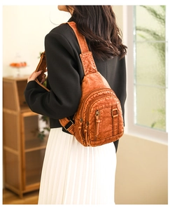 Close-up of brown washed leather chest bag with zipper detail and vintage texture
