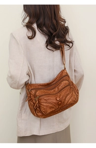 Brown vintage washed leather crossbody bag shown on a model against a neutral background