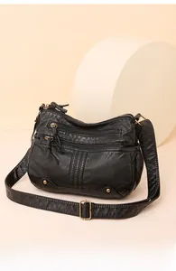 Gros plan du sac bandoulière en cuir lavé noir avec fermetures éclair et boucles en bronze